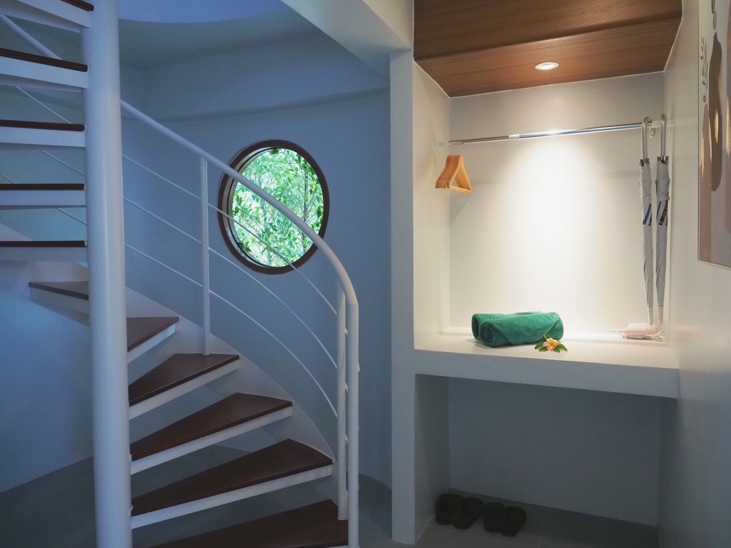 Eine moderne Treppe mit einem Rundfenster, einem integrierten Regal mit Handtuch und Zahnbürste sowie ein Paar Schuhe am Fuß.