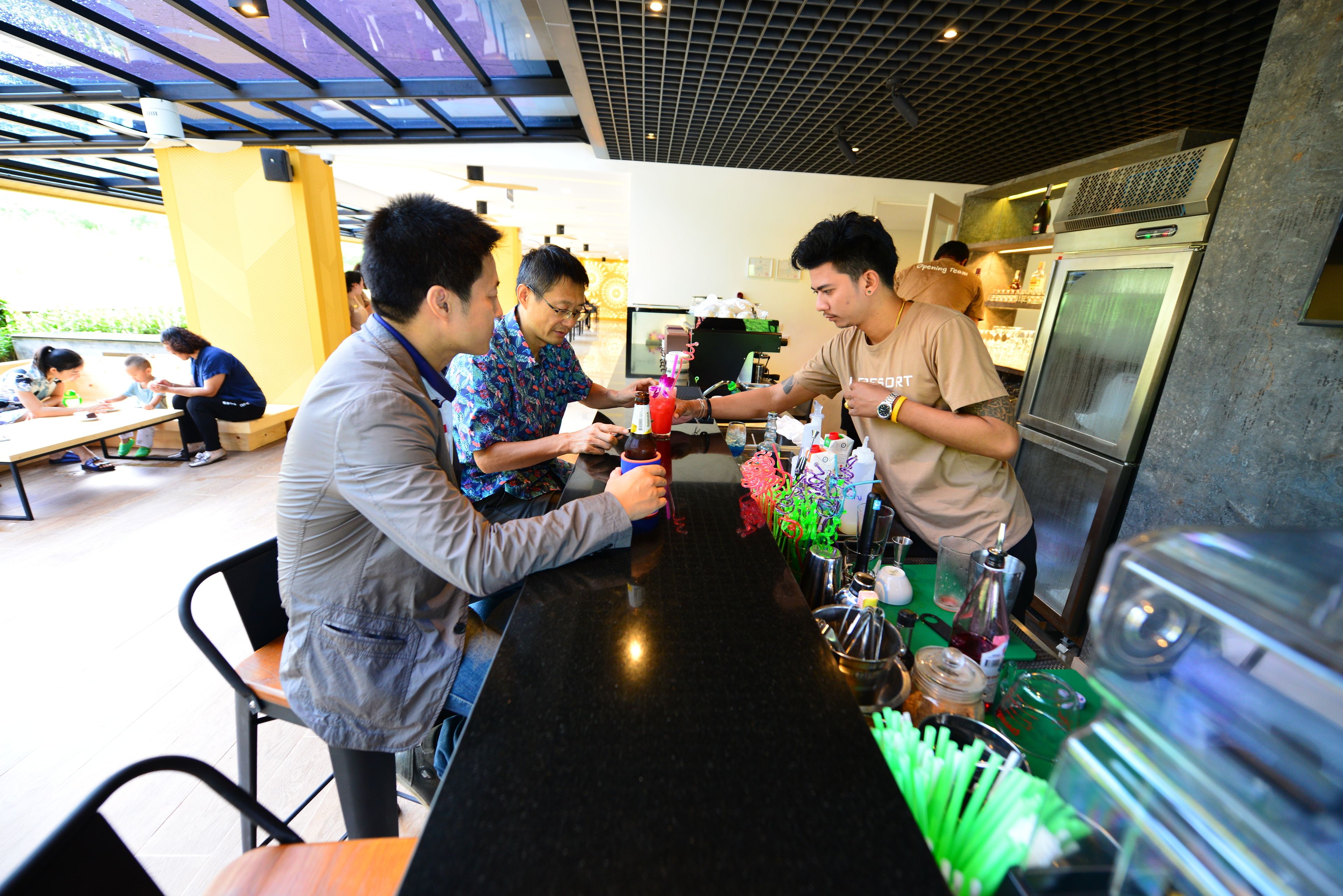 A bar area with a counter, stools, and a refrigerator.