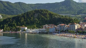 Eine Küstenstadt mit Strand, Gebäuden und einem Berg im Hintergrund.