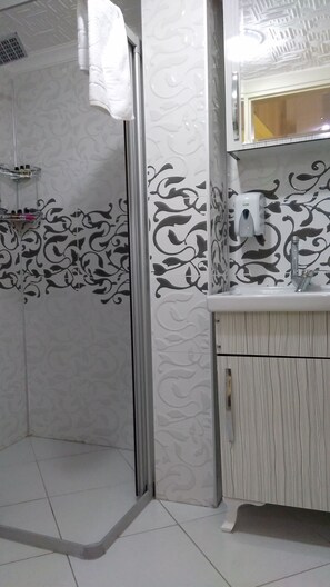 Un bany amb dutxa, un lavabo i un mirall.