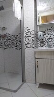 Un baño con ducha, lavamanos y espejo.
