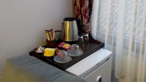 Eine kompakte Küchenzeile mit Kaffeemaschine, Wasserkocher, Salz- und Pfefferstreuern sowie einem kleinen Tisch mit Snacks.