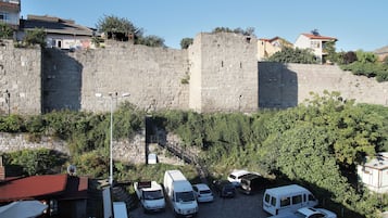 Un estacionamiento con varias camionetas blancas, un muro de piedra y edificios al fondo.