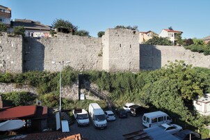 Un estacionamiento con varias camionetas blancas, un muro de piedra y edificios al fondo.