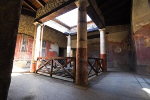 An ancient structure with stone walls, wooden beams, and a central open area with a wooden bench. - Il Timone Bed and Breakfast (Castellammare di Stabia)