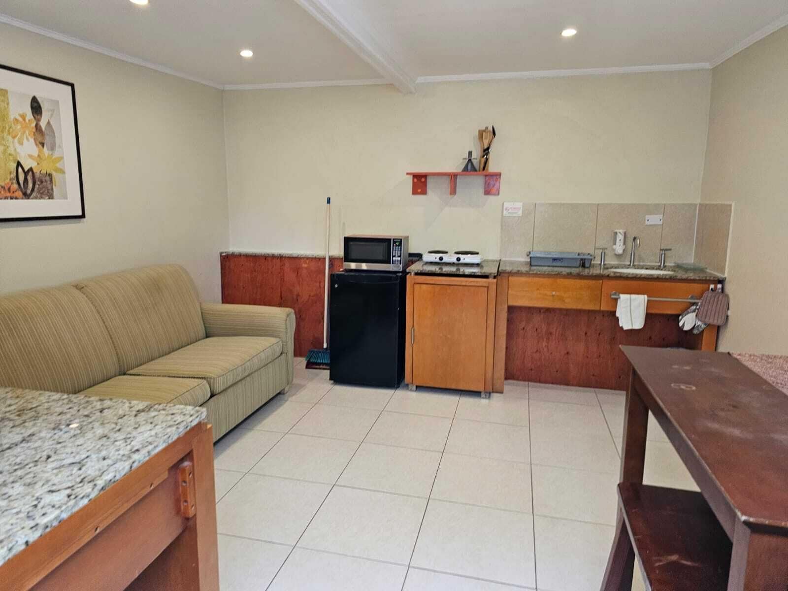Um espaço de estar compacto com sofá, cozinha compacta e mesa de jantar.