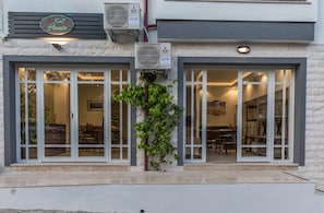 A building with large glass doors, air conditioning units, and a sign that reads "Kaš House".