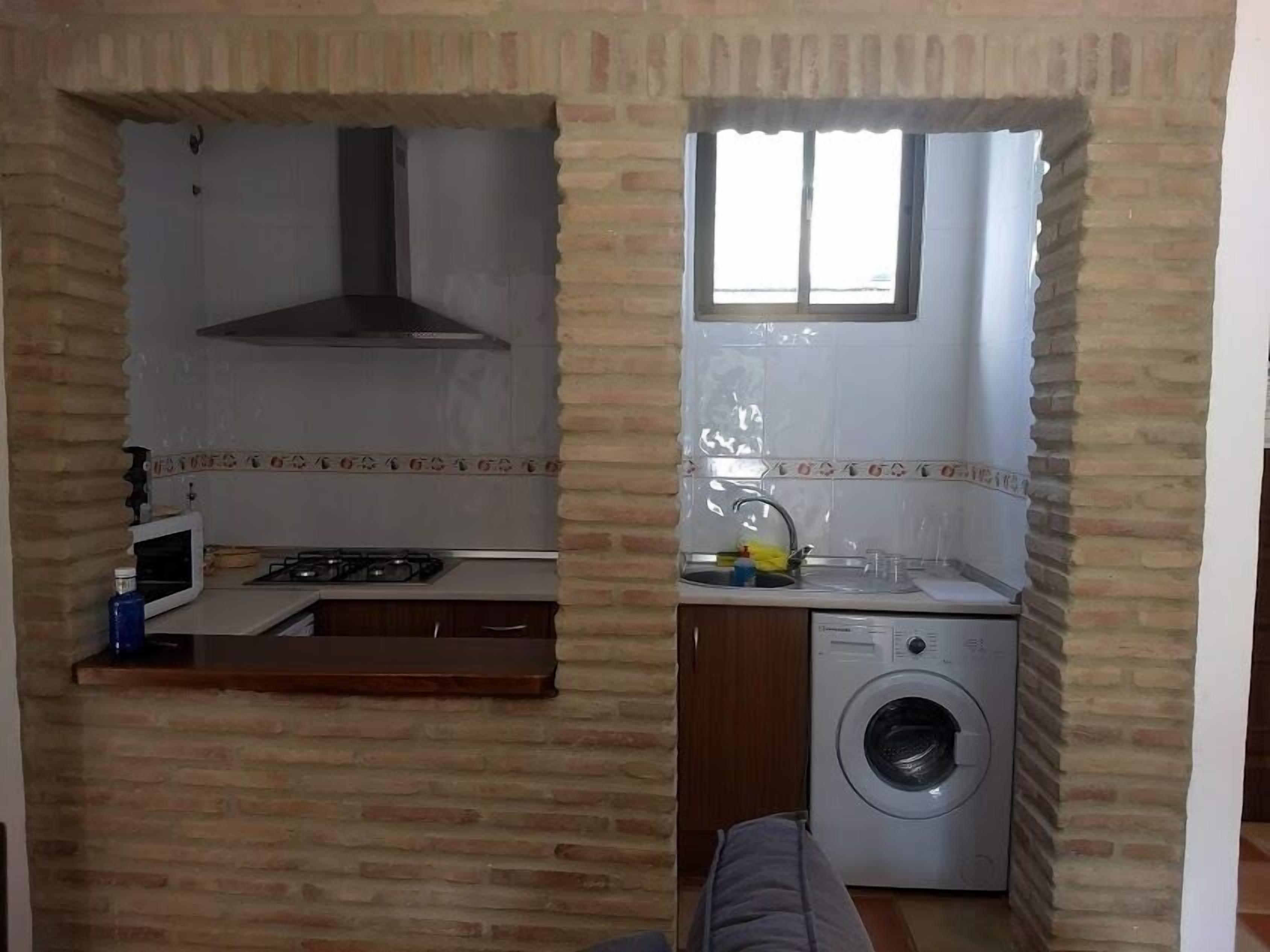 A compact kitchen with a microwave, stove, and sink, and a laundry area with a washing machine.