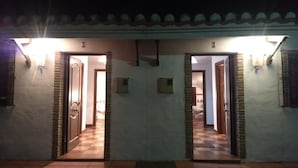 Un edificio con dos puertas, cada una que da a una habitación con suelo de baldosas y baño a la vista.