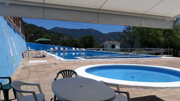 Zona de piscina con una piscina pequeña, una mesa y sillas.