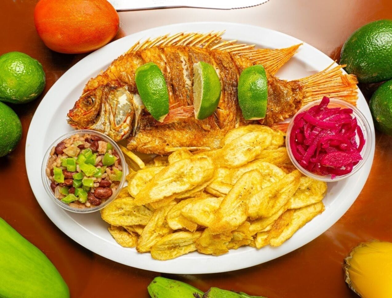 Un plato con pescado frito, papas fritas y dos acompañamientos de salsa.