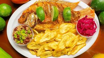 Un plato con pescado frito, papas fritas y dos acompañamientos de salsa.
