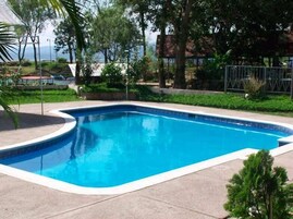 Una piscina rectangular con borde curvo, rodeada por una solana de hormigón.