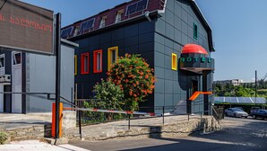 A modern hotel with a unique architectural design, featuring a prominent red dome and solar panels on the roof. - Route Hotel (Tbilisi)