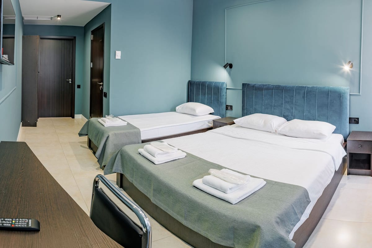 A hotel room with two beds, a desk, a chair, and a TV.