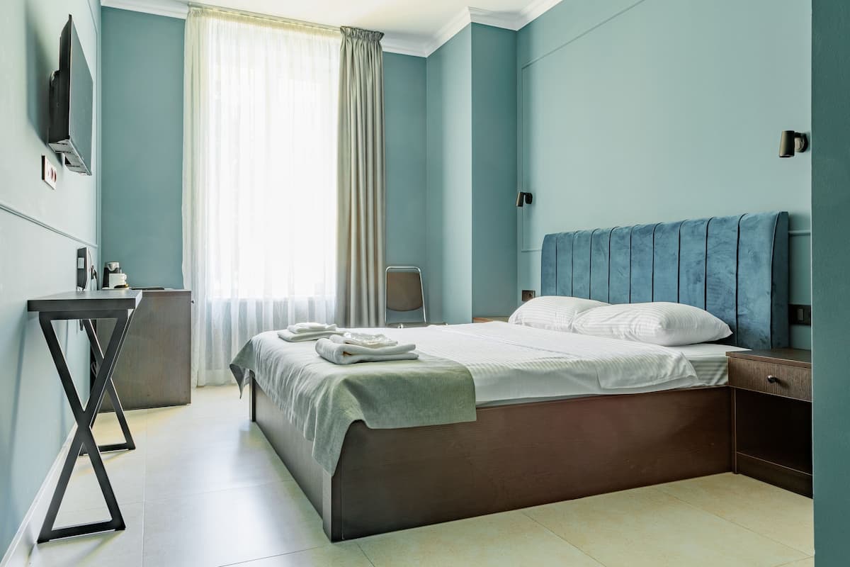A modern hotel room with a bed, a desk, and a TV.