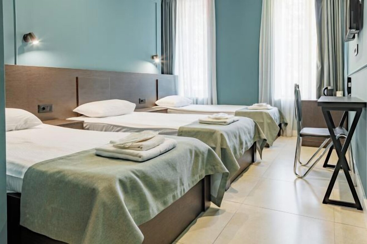 Ett hotellrum med tre sängar, ett skrivbord och en stol.