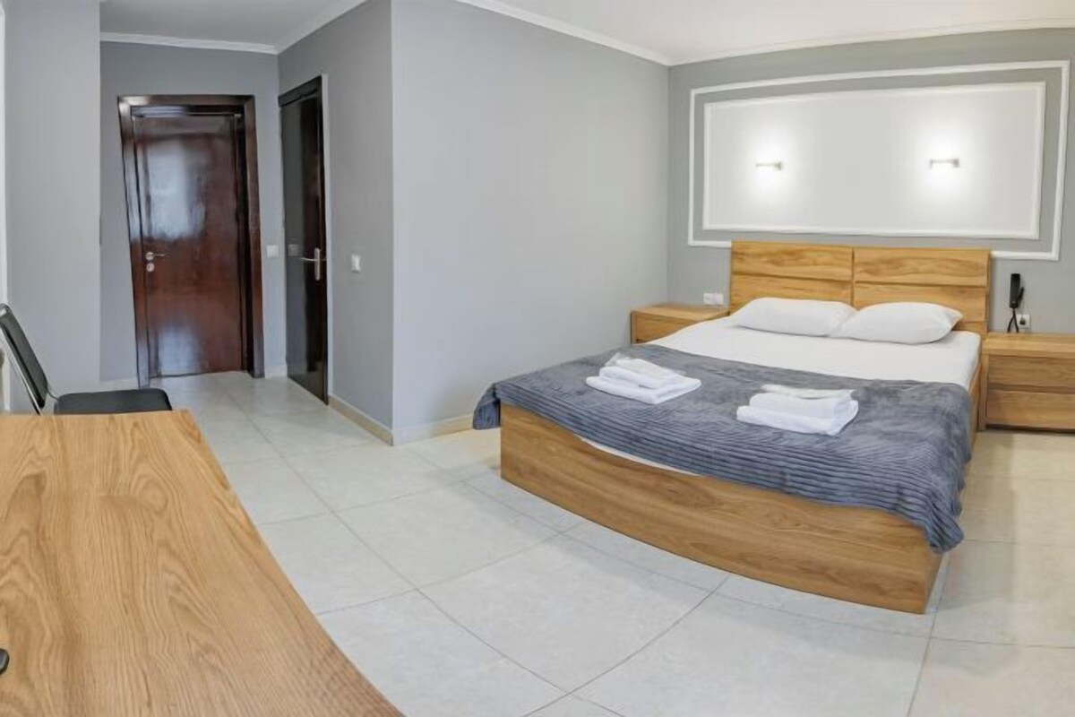 A bedroom with a wooden bed, a nightstand, a desk, and a chair.
