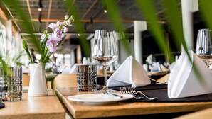 Una mesa de restaurante servida con una copa de vino, un vaso de agua, un plato y una servilleta.