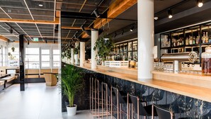 Zona de bar moderna con encimera de mármol, taburetes y una variedad de botellas y vasos.