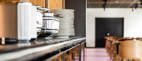 Montaje de bufé con platos apilados y una máquina de café.