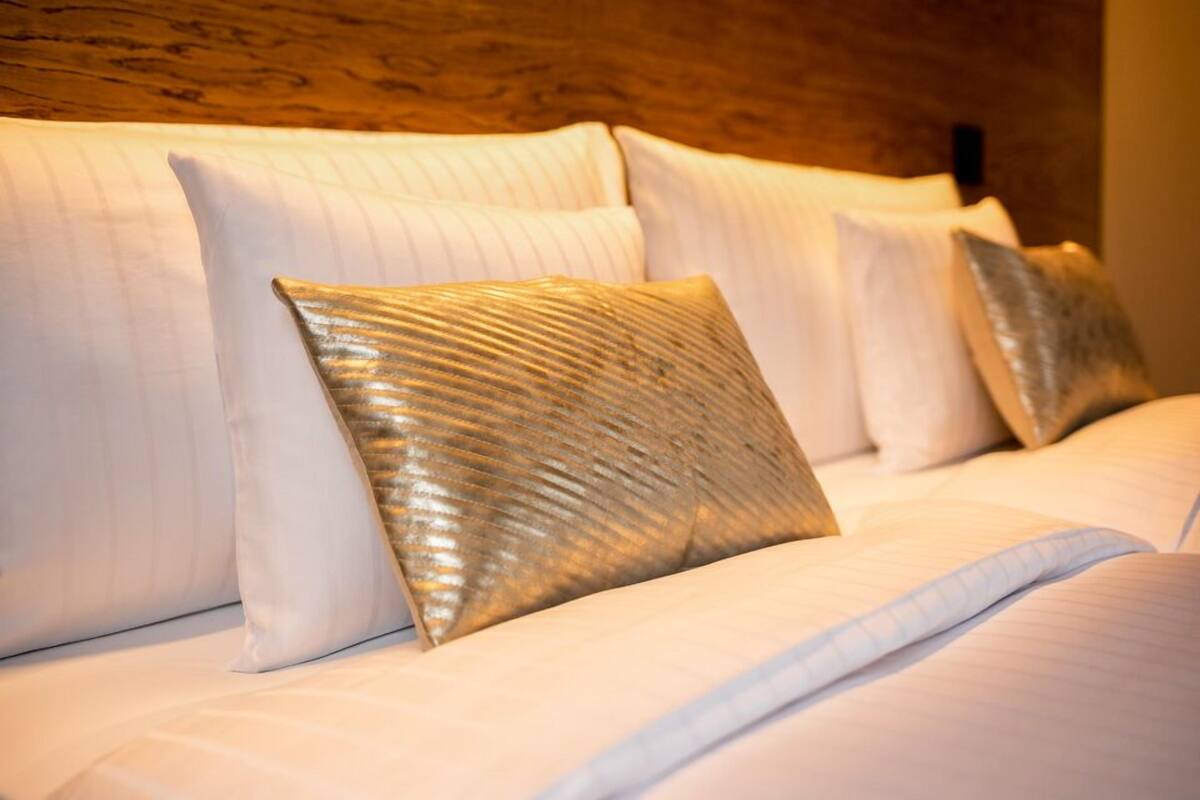 A neatly made bed with white linens and a single decorative pillow.