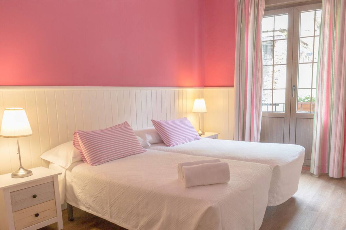 A double room with two beds, white bedding, and pink accents.