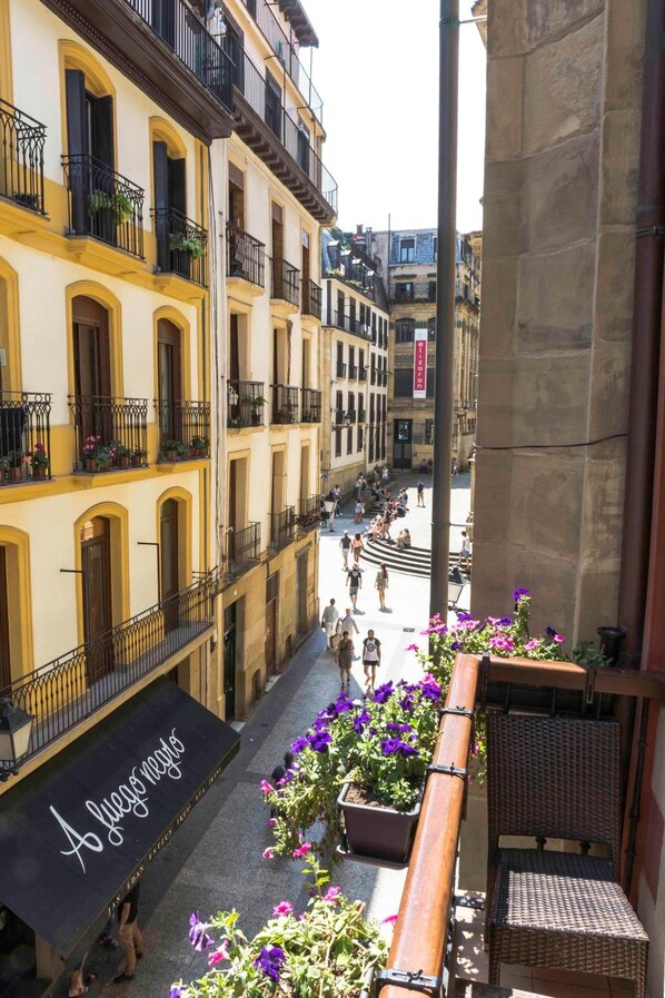 A narrow street with yellow buildings, outdoor seating, and a sign reading "A juego limpio".
