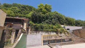 A building with a balcony overlooking a lush green hillside. - Pensión Amaiur (San Sebastián)