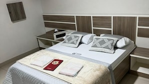 A neatly arranged hotel room with a bed, bedside tables, and a small cabinet. - Hotel Cumbica (Guarulhos)
