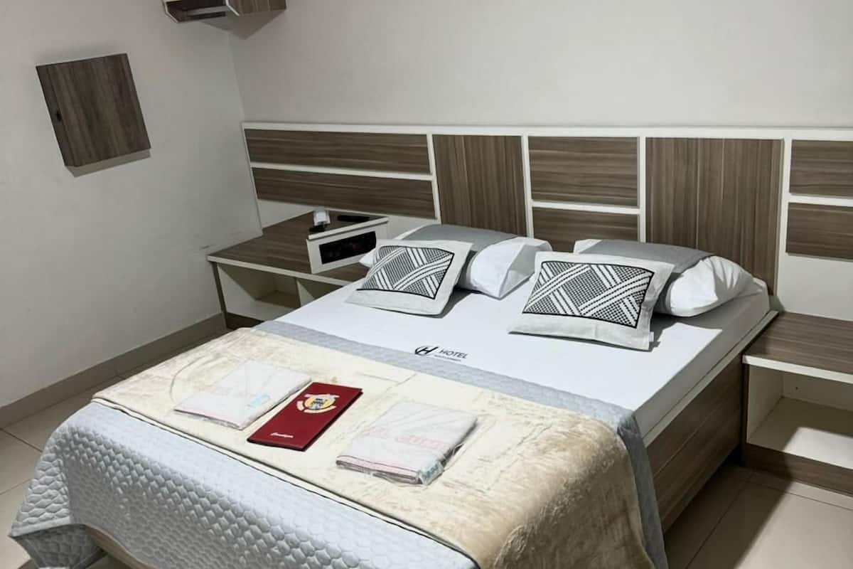 Une chambre d’hôtel bien rangée, avec un lit, des tables de chevet et un petit meuble.