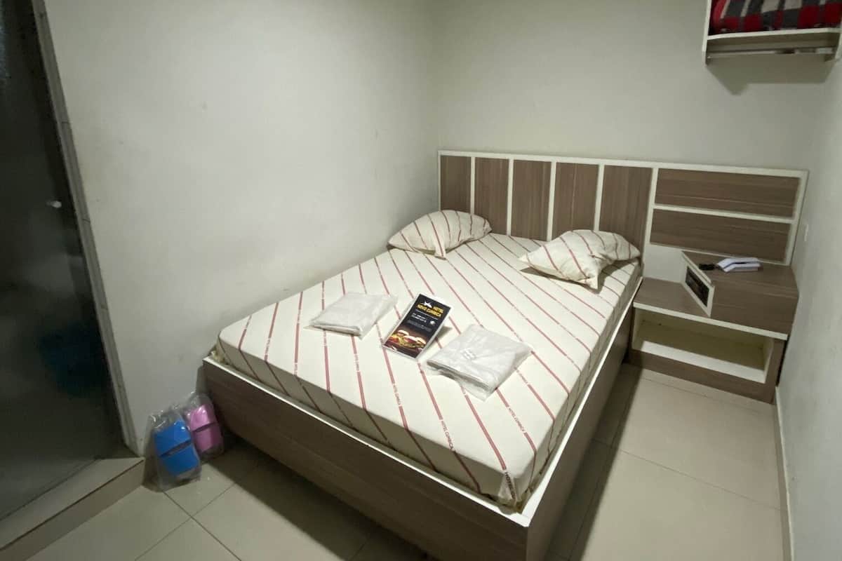 Une chambre à coucher bien rangée, avec un lit, des tables de chevet, un luminaire suspendu et une petite étagère.