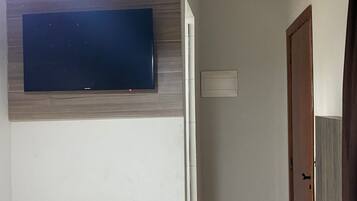 A hallway with a flat-screen TV mounted on the wall, a door, and a ceiling light.