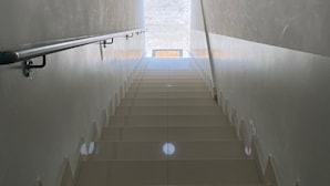 A staircase with a handrail, leading to a bright area at the top. - Hotel Cumbica (Guarulhos)