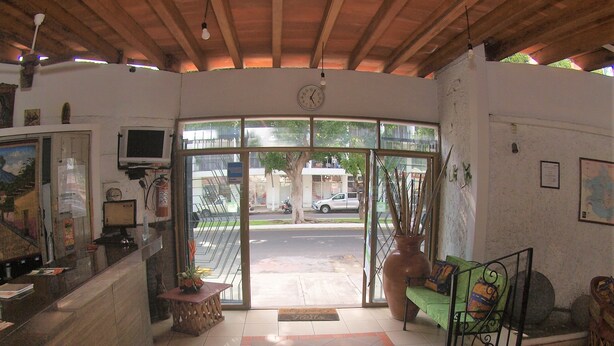 A reception area with a desk, a television, and a large window overlooking a street. - Hotel Hospedajes Del Rey (Colima)