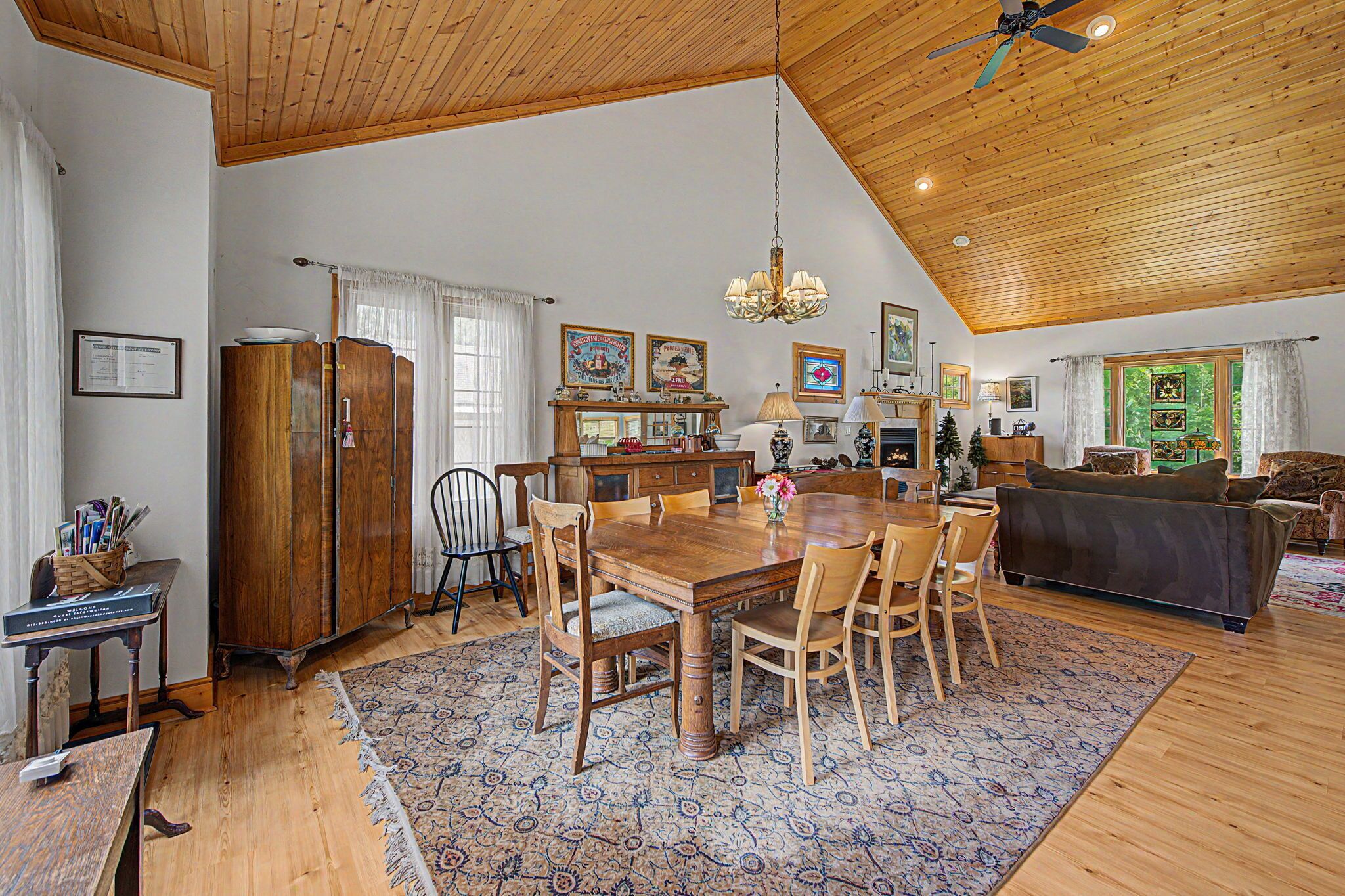 A spacious dining area with a wooden table and chairs, a chandelier, and a fireplace.