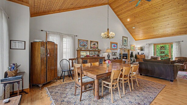 Un comedor amplio con una mesa y sillas de madera, un candelabro y una chimenea.