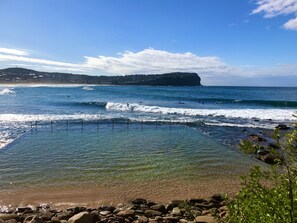 A beach with clear water, waves, and a rocky shoreline.