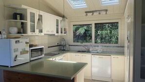 A modern kitchen with white cabinets, a wooden island, a built-in microwave, and a window with a view of greenery.