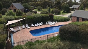 A swimming pool with lounge chairs and a brick patio. -  Prom Coast Holiday Lodge (Waratah North)