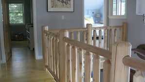 Eine Holztreppe führt zu einem Schlafzimmer mit einem Bett, einem Nachttisch und einer Lampe.