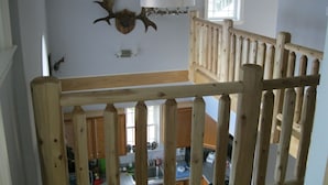 Ein Zimmer mit hohen Decken, einer Holzwandleiste, einem aufgehängten Hirschgeweih und einem Fenster mit Ausblick.