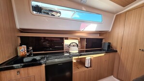Ett kompakt kök med en svart bänkskiva, en kaffebryggare och en flaska diskmedel.