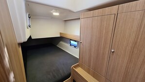 Ett kompakt och väl upplyst inre utrymme med en säng, ett träskåp och en liten hylla.