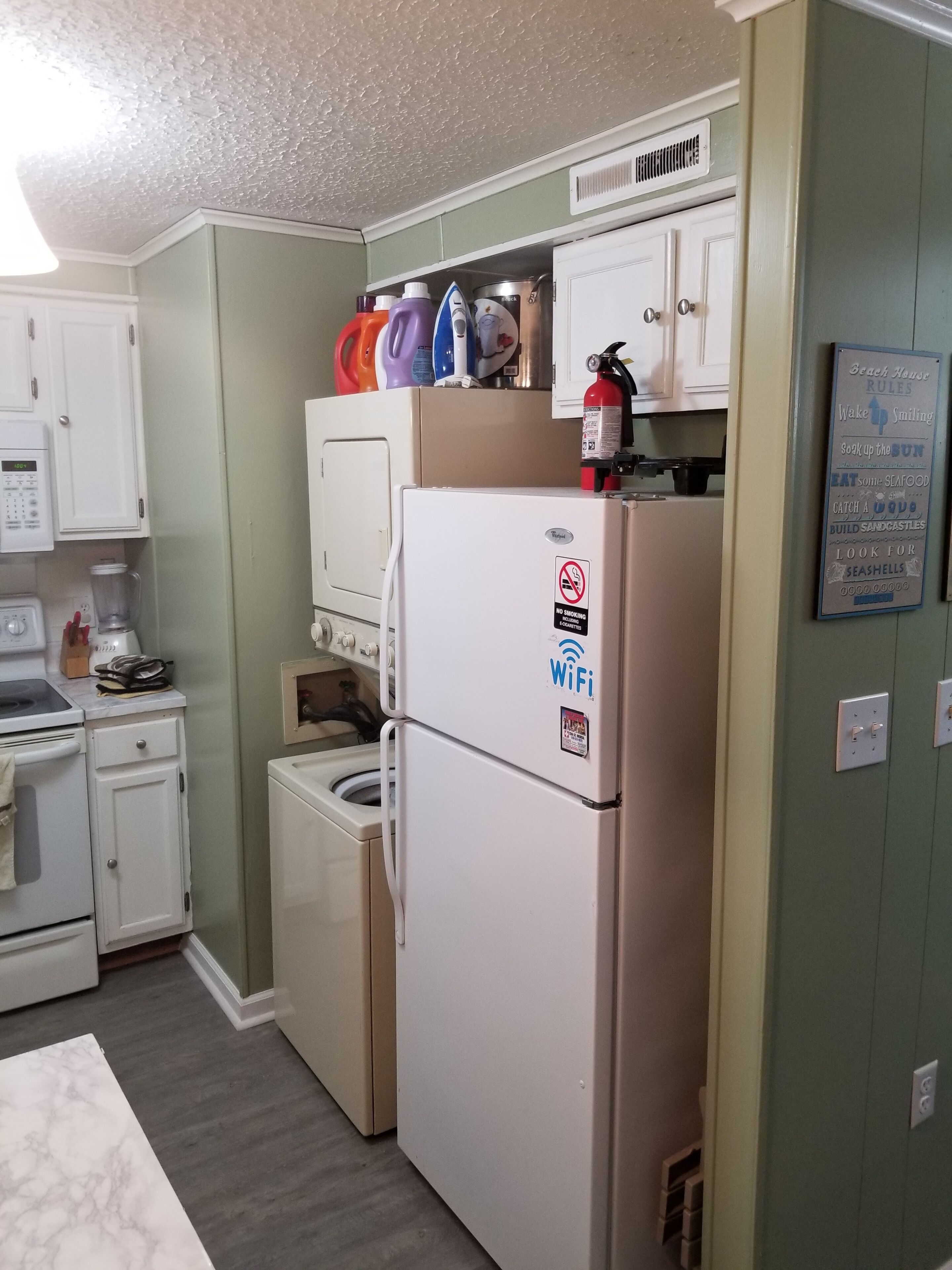 A compact kitchen with a refrigerator, a washing machine, and a microwave.