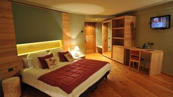 A bedroom with a large bed, a desk, and a television.