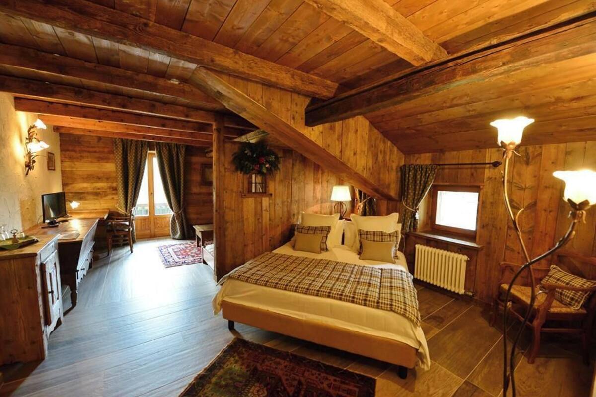 Une chambre confortable dans un chalet en bois, avec un grand lit, un bureau et une chaise.