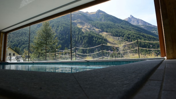 A pool with a mountain view, wooden deck, and a rope barrier. - La Madonnina del Gran Paradiso (Cogne)