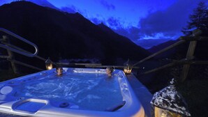 A hot tub with a mountain view, surrounded by wooden railings and lit by lanterns. - La Madonnina del Gran Paradiso (Cogne)