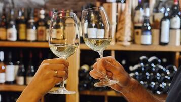 Dos manos sosteniendo copas de vino, con un fondo borroso de botellas.